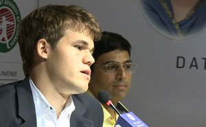 Carlsen concentrating on his press conference answers with wistful Anand in the background. Photo © 